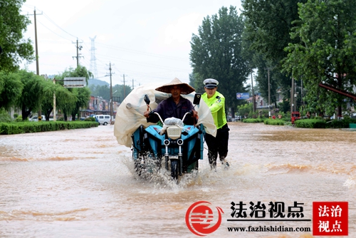 7月14日，山东省枣庄市公安局山亭分局交警大队辅警，帮助群众及时将受困车辆推离积水区。.jpg