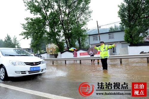 7月14日，山东省枣庄市公安局山亭分局交警大队民警冒雨指挥车辆安全通行。.jpg
