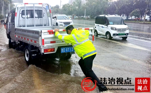 7月14日，山东省枣庄市公安局山亭分局交警大队组织警力冒雨疏导交通，及时将受困车辆推离积水区。.jpg